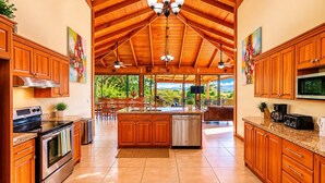 Una cocina amplia con armarios de madera, una isla grande, electrodomésticos de acero inoxidable y vistas al exterior.