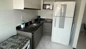 Una cocina moderna con armarios blancos, estufa a gas, microondas y refrigerador.