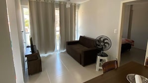 Amplia sala de estar con sofá, mesa de comedor y ventilador de techo.