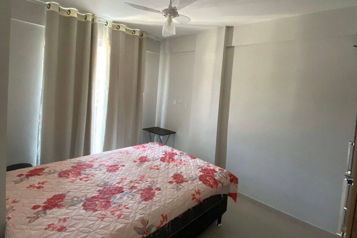 Une chambre à coucher avec un lit, un ventilateur de plafond, une petite table et une porte.
