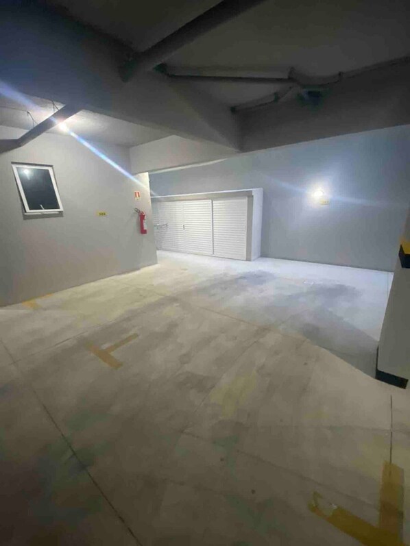 A spacious indoor area with a concrete floor, a closed garage door, and a small window. - Arraial do Cabo (Arraial do Cabo)