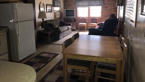 A compact living space with a refrigerator, sofa, TV, and a dining table.