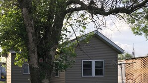 A small, single-story house with a sloped roof, a front porch, and a visible window.