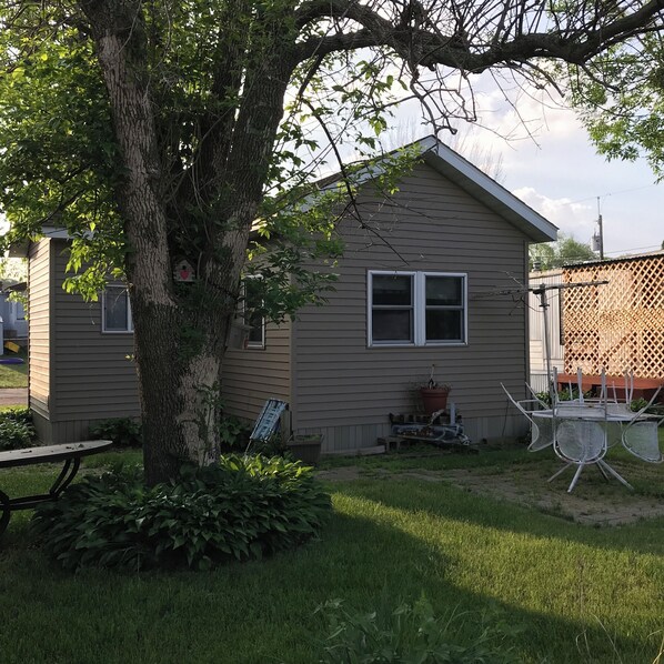 A small, single-story house with a sloped roof, a front porch, and a visible window. - Sunset Waters: Serene Retreat on the Mississippi River Shoreline Fisher Friendly (Stoddard)
