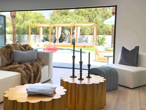 A modern living room with a sofa, a coffee table, and a view of an outdoor swing set and pool. - *NEW* Boca Beach Resort! Location, golf, pool  (Scottsdale)
