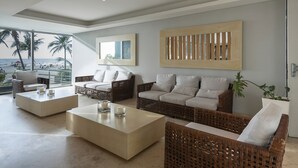 A modern living room with wicker furniture, a large abstract painting, and a view of the beach. - Cartagena Home with a Heavenly View (Cartagena)
