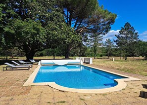 Relax by the serene pool surrounded by mature trees and a lush lawn.