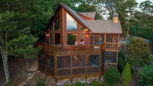Una cabaña con balcón, ventanas amplias y chimenea.