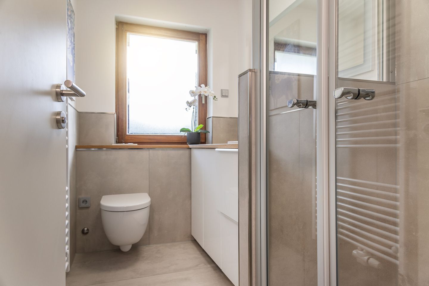 A compact bathroom with a toilet, a small window, and a shower area.