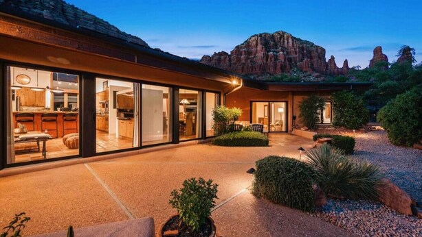 A modern house with large glass windows, a patio, and a garden with desert plants. - Chapel Vista Home With Stunning Views of Red Rocks & Chapel. Hot-Tub & Gardens. (Sedona)