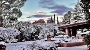 A snow-covered garden with a gazebo, a fountain, and a view of red rock formations in the background. - Chapel Vista Home With Stunning Views of Red Rocks & Chapel. Hot-Tub & Gardens. (Sedona)