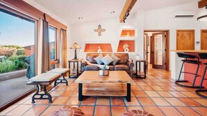 A spacious living room with a large window, a wooden coffee table, a sofa, and a small side table. - Chapel Vista Home With Stunning Views of Red Rocks & Chapel. Hot-Tub & Gardens. (Sedona)