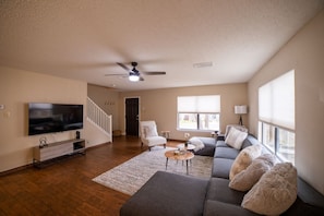 Relax in this stylish living room with a flat-screen TV, comfortable sofa, and cozy armchair.