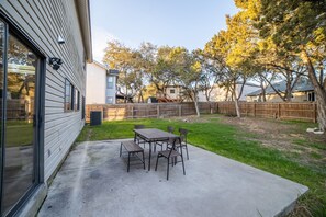 Enjoy outdoor dining or relaxation in this backyard with a patio, lawn, and trees.