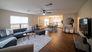 Un salón amplio con un sofá gris, una mesa de centro y un comedor con mesa y sillas.