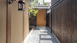 A narrow alleyway with a wooden door at the end, a lantern on the left, and a wooden fence on the right. - Certify Kyomachiya [Himoewya] Fully furnished house with a walk to Kiyomizu-dera Temple, Chiji-in Temple, Yasaka Shrine and Kyoto National Museum of Art. (京都市)