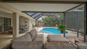 A covered outdoor seating area with a pool, a dining table, and chairs. - Spacious Beachy Retreat with Heated Pool! Short walk to beach•Pet friendly•Bikes (St. Augustine)