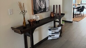 Een modern interieur met een houten console tafel, een schilderij van een paard, en een eethoek op de achtergrond.