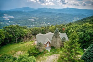 A house surrounded by lush greenery and mountains in the background.