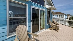Une maison bleue avec une terrasse, deux portes-fenêtres coulissantes et deux fauteuils Adirondack.