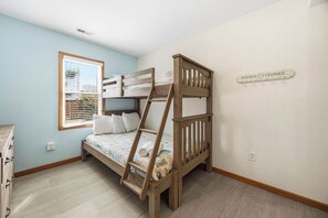 Un lit superposé avec une échelle, une fenêtre avec des stores et un panneau fixé au mur.