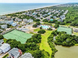 Vista aerea di una zona residenziale con case, campi da tennis e una spiaggia.