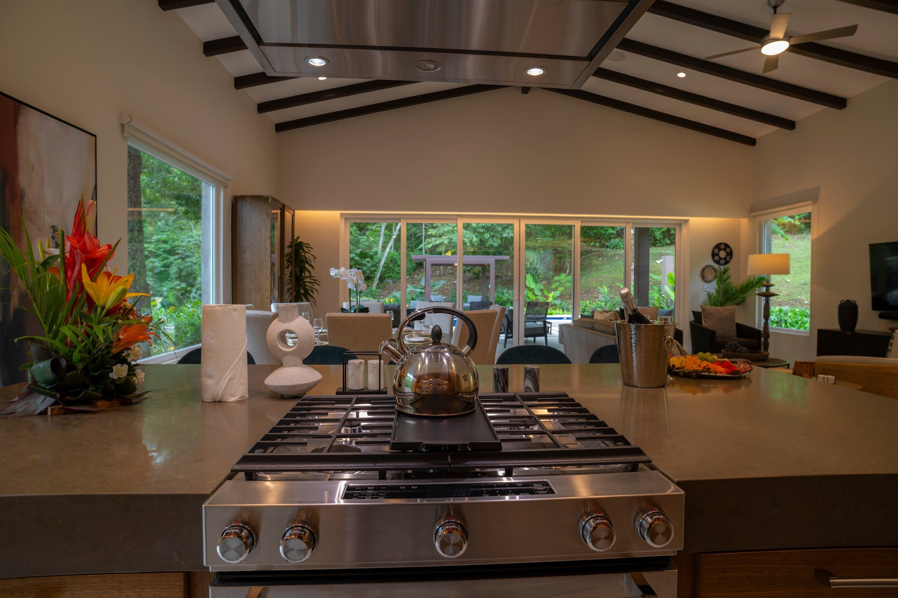 Una cocina moderna con estufa de acero inoxidable, ventanas amplias y ventilador de techo.