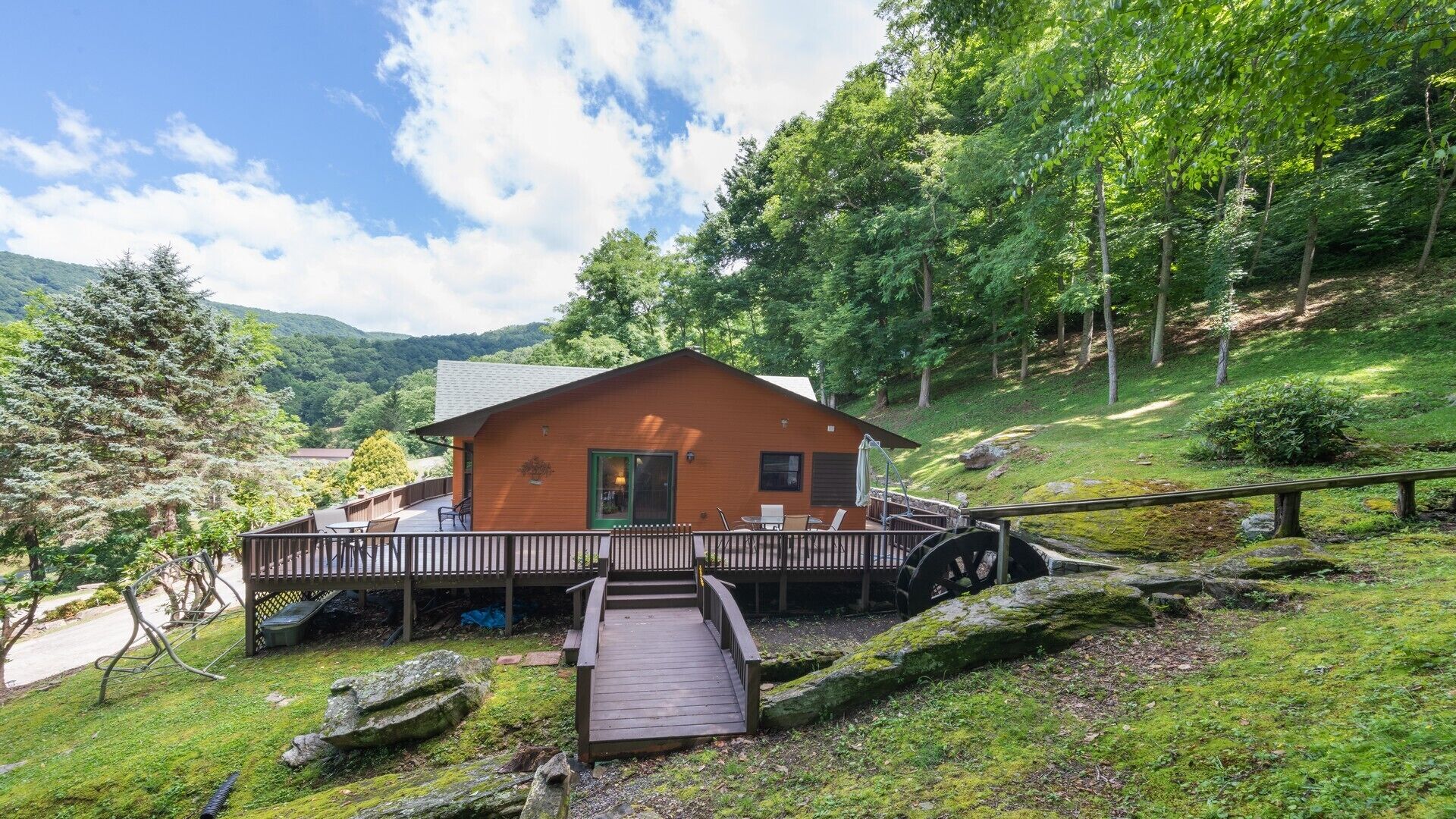 A cabin with a wooden deck, a small porch, and a wooden staircase leading to the entrance.