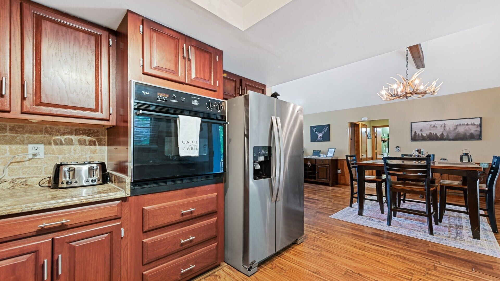 A modern kitchen with wooden cabinets, a stainless steel refrigerator, and a built-in oven.