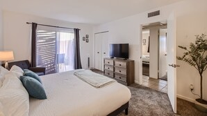 Une chambre à coucher avec un lit, une commode, un téléviseur et une plante en pot.