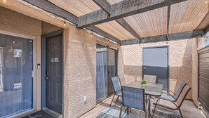 Un patio couvert comprenant une table et des chaises en verre, une porte et une porte-fenêtre coulissante.