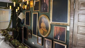 Eine Wand mit gerahmten Kunstwerken und einer dekorativen Leuchte.