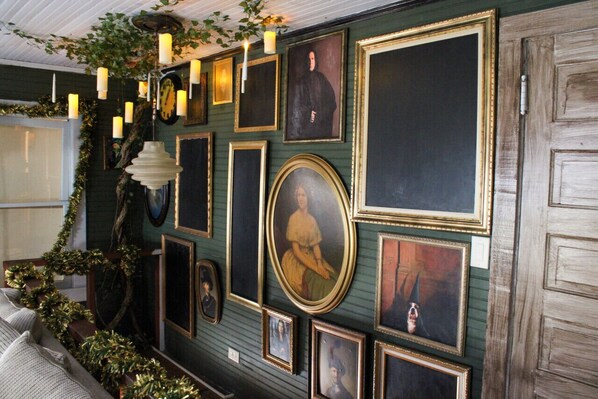 Un mur orné de tableaux encadrés et agrémenté d’un luminaire décoratif.