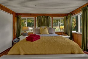 Un dormitorio con una cama grande, dos mesitas de noche y una ventana con cortinas.