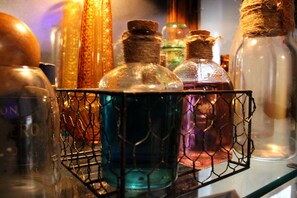 A collection of glass bottles with cork stoppers, some with labels, arranged on a wire rack.