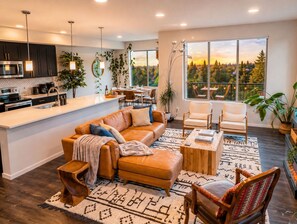 A modern kitchen with a central island, dining area with chairs, a sofa, and a view of a forest through large windows. - Seattle Luxury • FIFA World Cup • Scenic Views (Seattle)