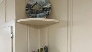 A corner cabinet with three shelves, each holding different items. - Lida's Place - 3 BR 2 BA Ranch House - 7.6 miles to Grenada Lake (Grenada)