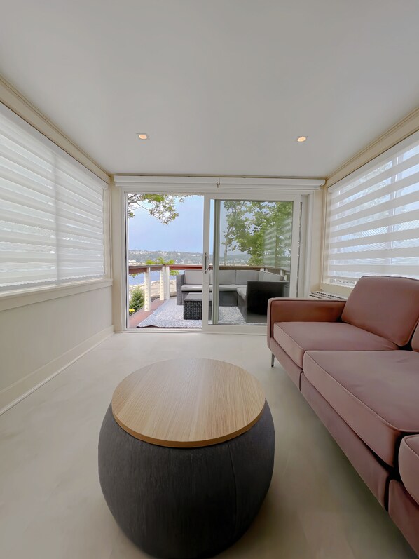 A modern living room with a round coffee table, a pink sofa, and a sliding glass door leading to an outdoor patio.