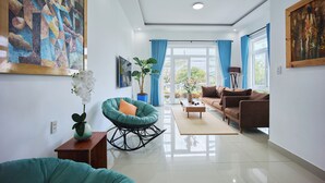 A spacious living room with a sofa set, a rocking chair, and a coffee table. - Nelly Villa  | Copia Villa Hoi An (Thành phố Hội An)