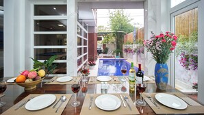 A dining table set for four with a view of a swimming pool and garden. - Nelly Villa  | Copia Villa Hoi An (Thành phố Hội An)