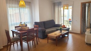 A living room with a sofa, dining table, chairs, and a coffee table. - VISTA SEGARIA Apartment in Vergel (Verger (el))