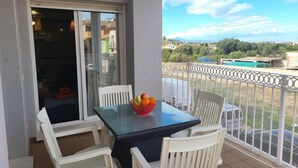 A balcony with a glass table and white chairs, a bowl of fruit, and a view of a residential area. - VISTA SEGARIA Apartment in Vergel (Verger (el))