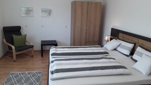 A bedroom with a bed, a chair, a wardrobe, and a small table. - Apartment "Bieniussa 3" with Private Garden & Wi-Fi (Gemünden am Main)