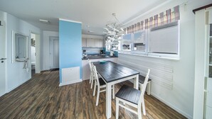 Una cocina moderna con armarios blancos, una mesa de comedor con sillas y una ventana con persianas.