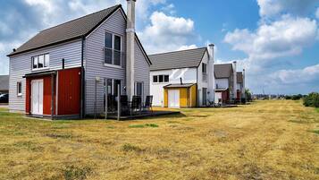 A row of single-story houses with attached garages, a grassy yard, and a clear sky.