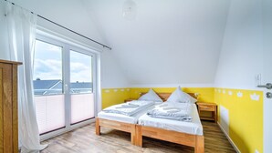Un dormitorio con una cama de madera, un ventanal con cortinas y una pared amarilla.