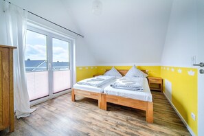 Ein Schlafzimmer mit einem hölzernen Bett, einem Fenster mit Vorhängen und einer gelben Wand.