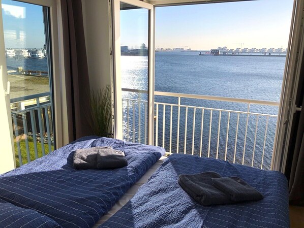 Una habitación con una cama, vistas de un río y un balcón con barandilla.