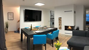 Una sala de estar moderna con comedor, televisor de pantalla plana, chimenea y sofá.