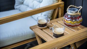 A wooden table with two glasses of coffee and a decorative jar.